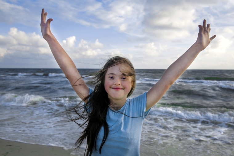 Portrait of down syndrome girl smiling on background of the sea